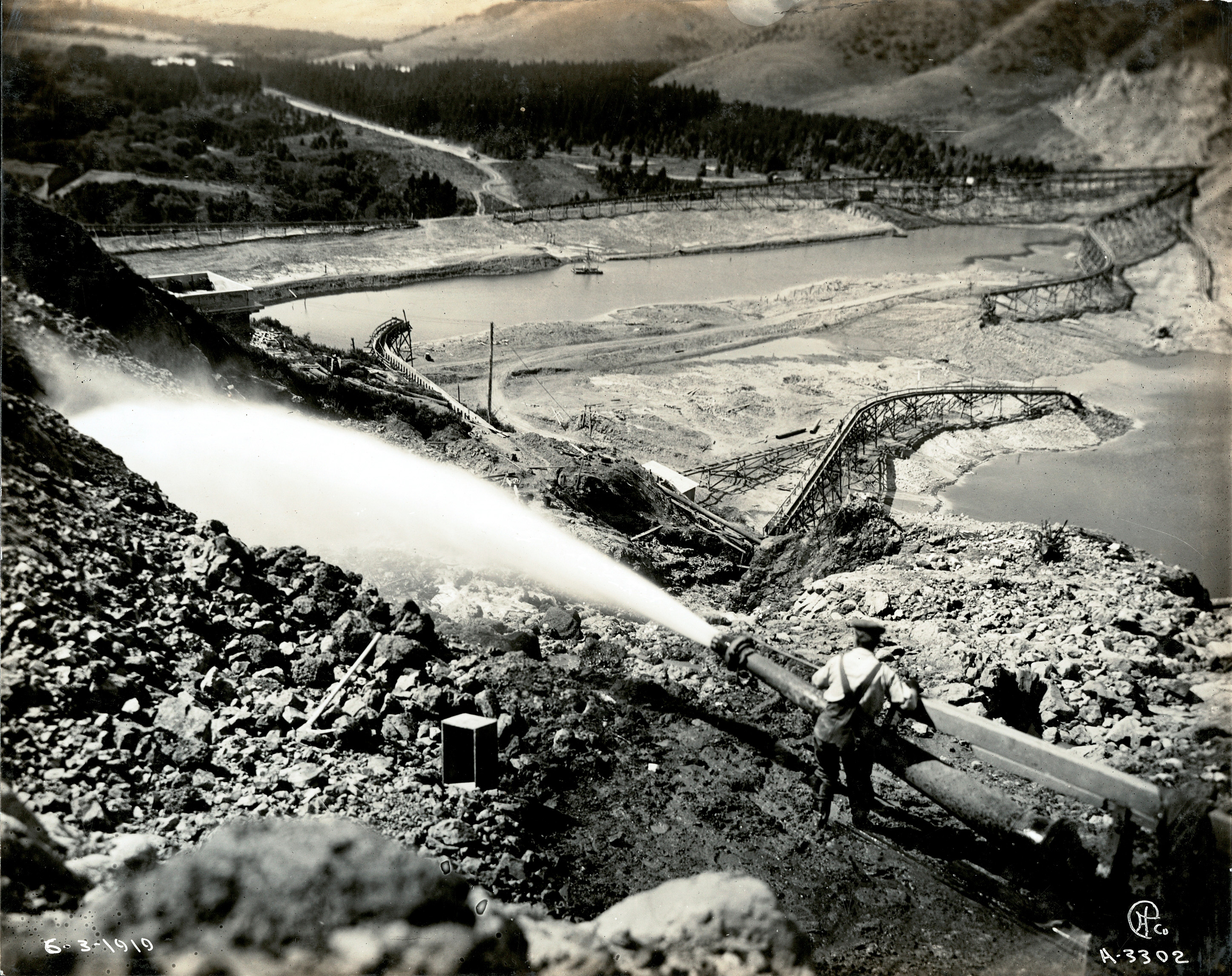 Miner using hydraulic hose to clear land while mining for gold